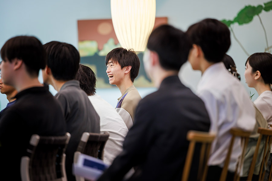 Group of attendees seated in a conference room, one young man in the center laughing.